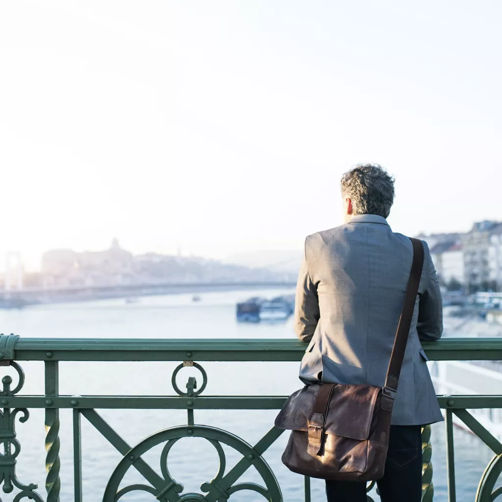 Man stood looking out off a bridge.