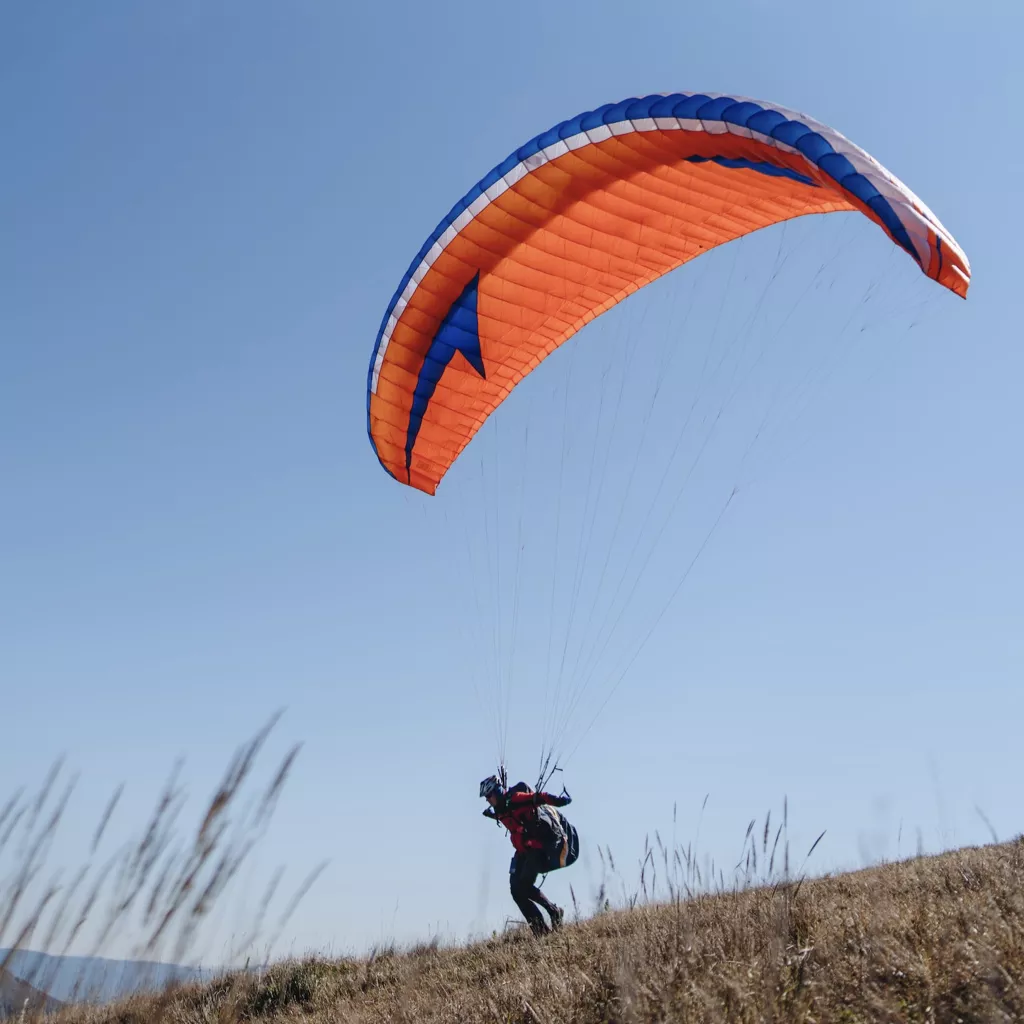 Person being brave, about to jump off a hill with a paraglider.