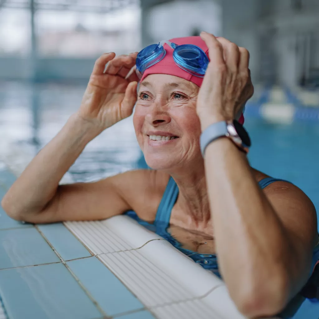 Retired lady, looking very healthy, enjoying time in a swimming pool.