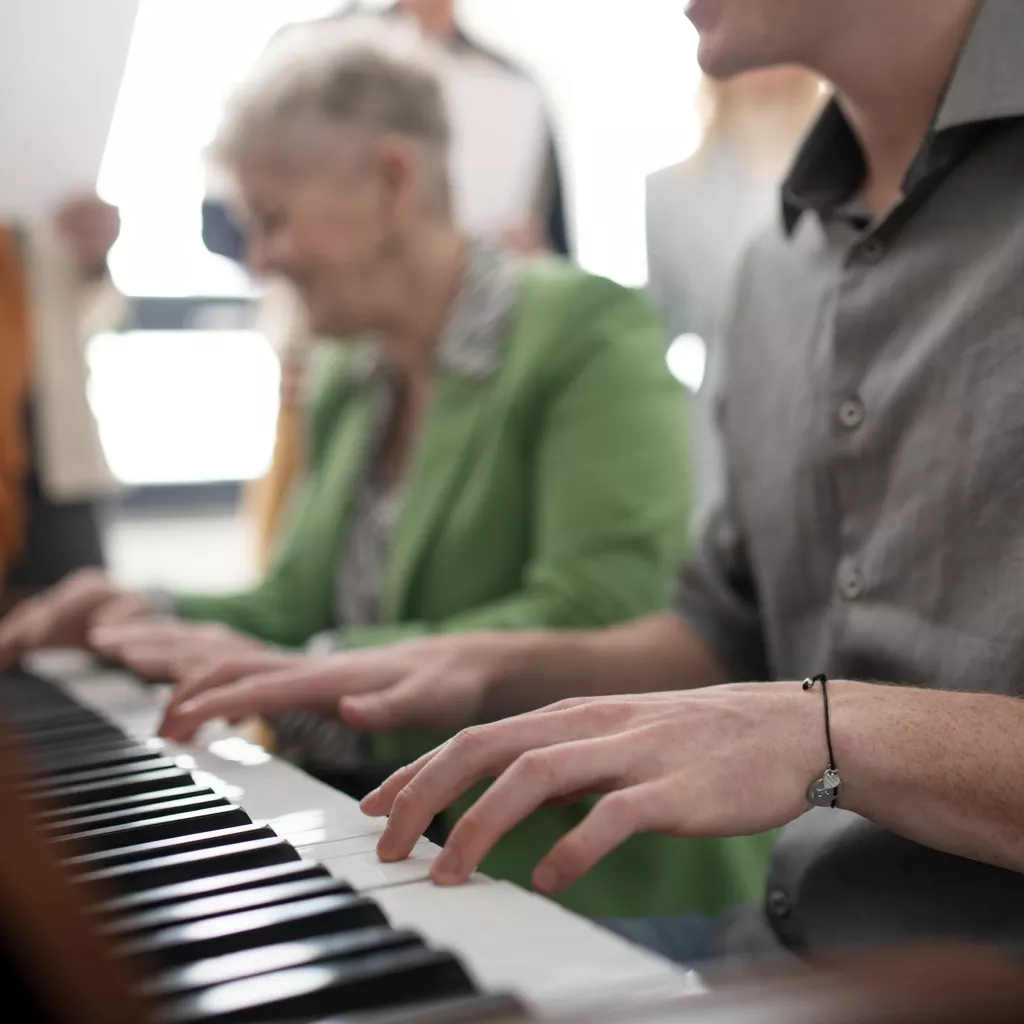 Two adults playing the piano together.
