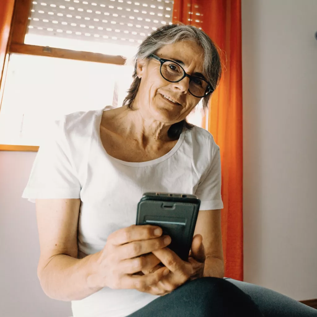 A retired lady holding her phone.