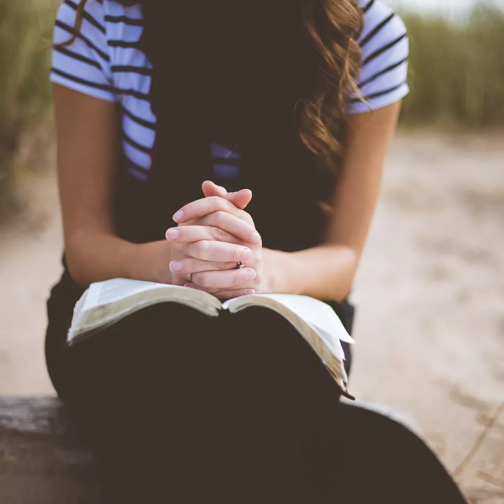 A lady praying as she reads the bible.