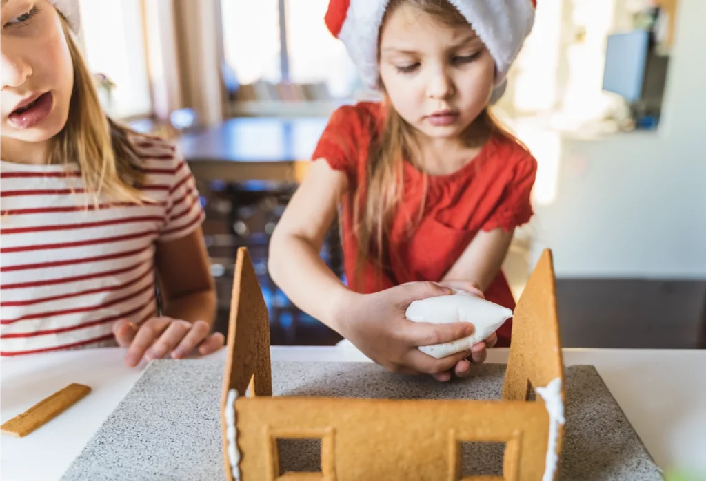 A girl decorating her gingerbread house.