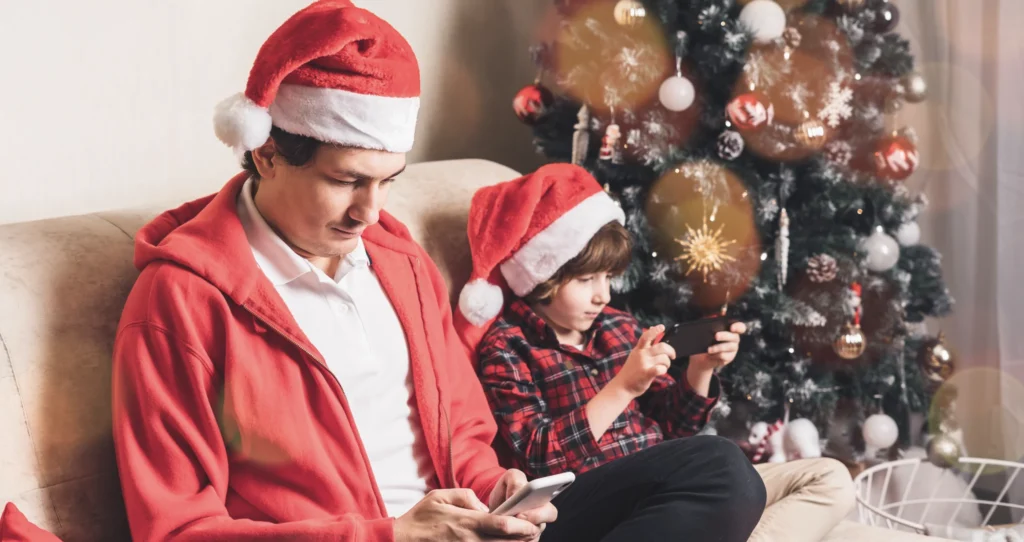A father and son ignore each other at Christmas as they play on their mobile devices.