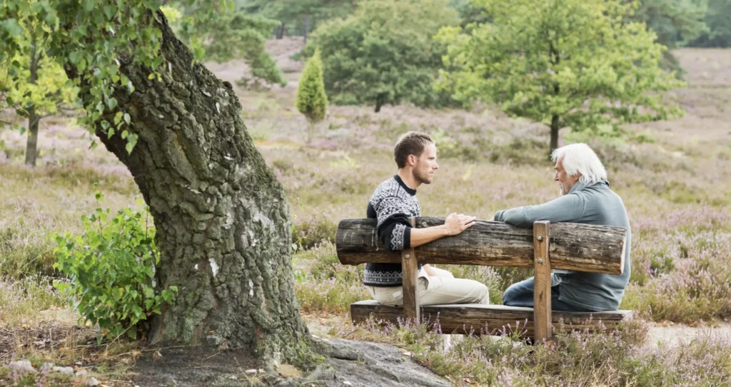 Two adults sharing family stories sat under a tree.